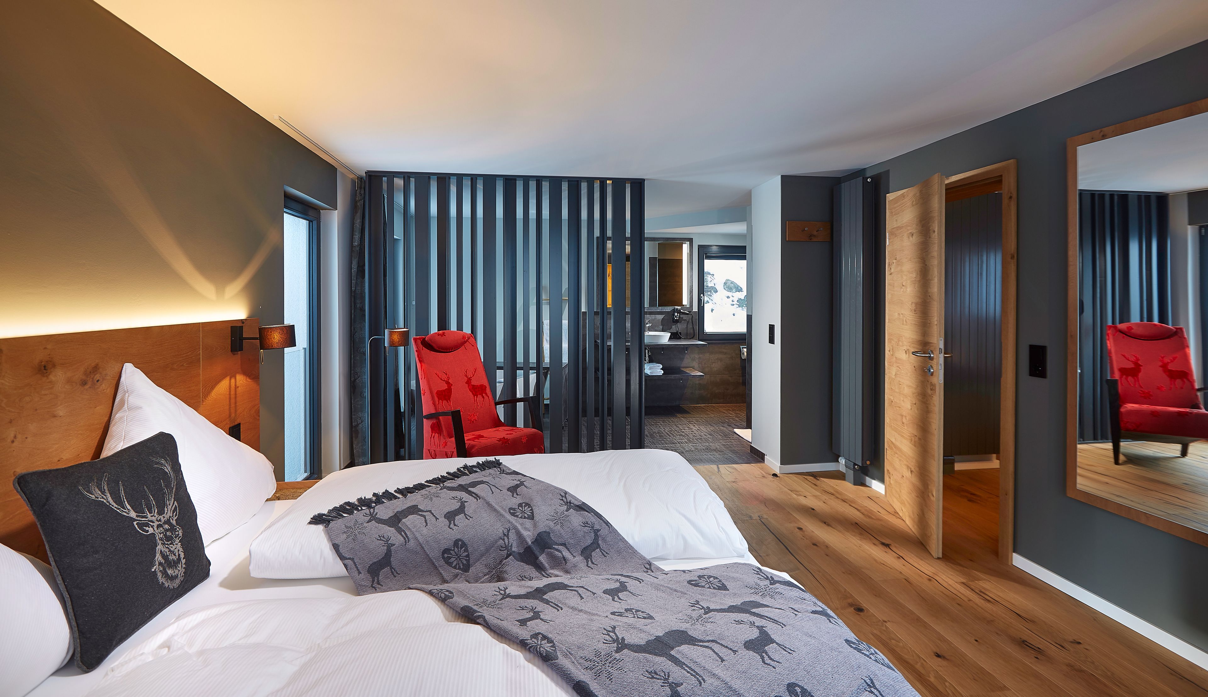 Una habitación de hotel moderna con una cama grande, una silla roja y un cabecero de madera.