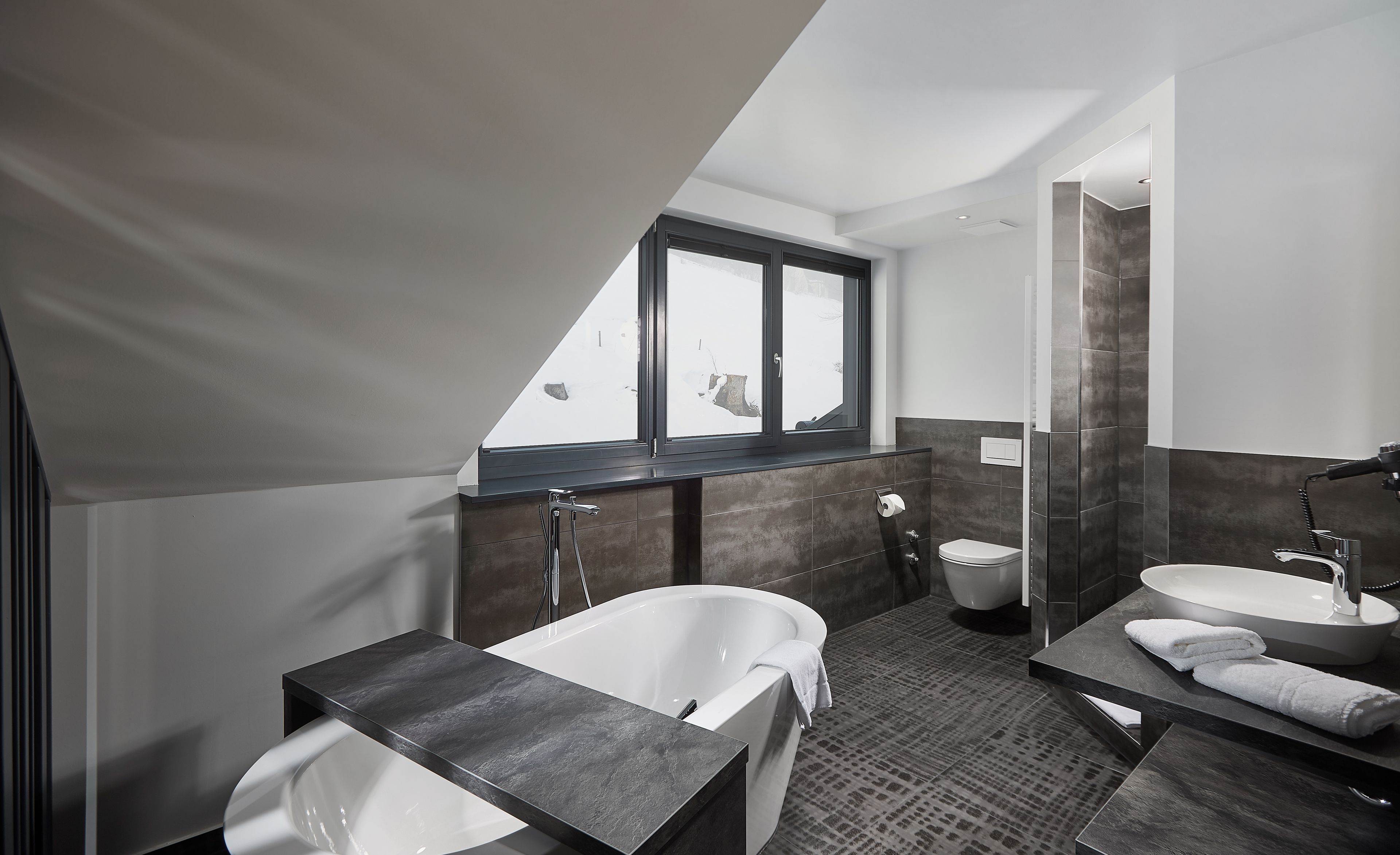 Ein modernes Badezimmer mit freistehender Badewanne, einem separaten Waschbecken und einer Toilette.