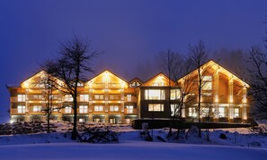 A multi-story lodge with a symmetrical facade, large windows, and a snow-covered landscape. - Black Forest Lodge (Feldberg)