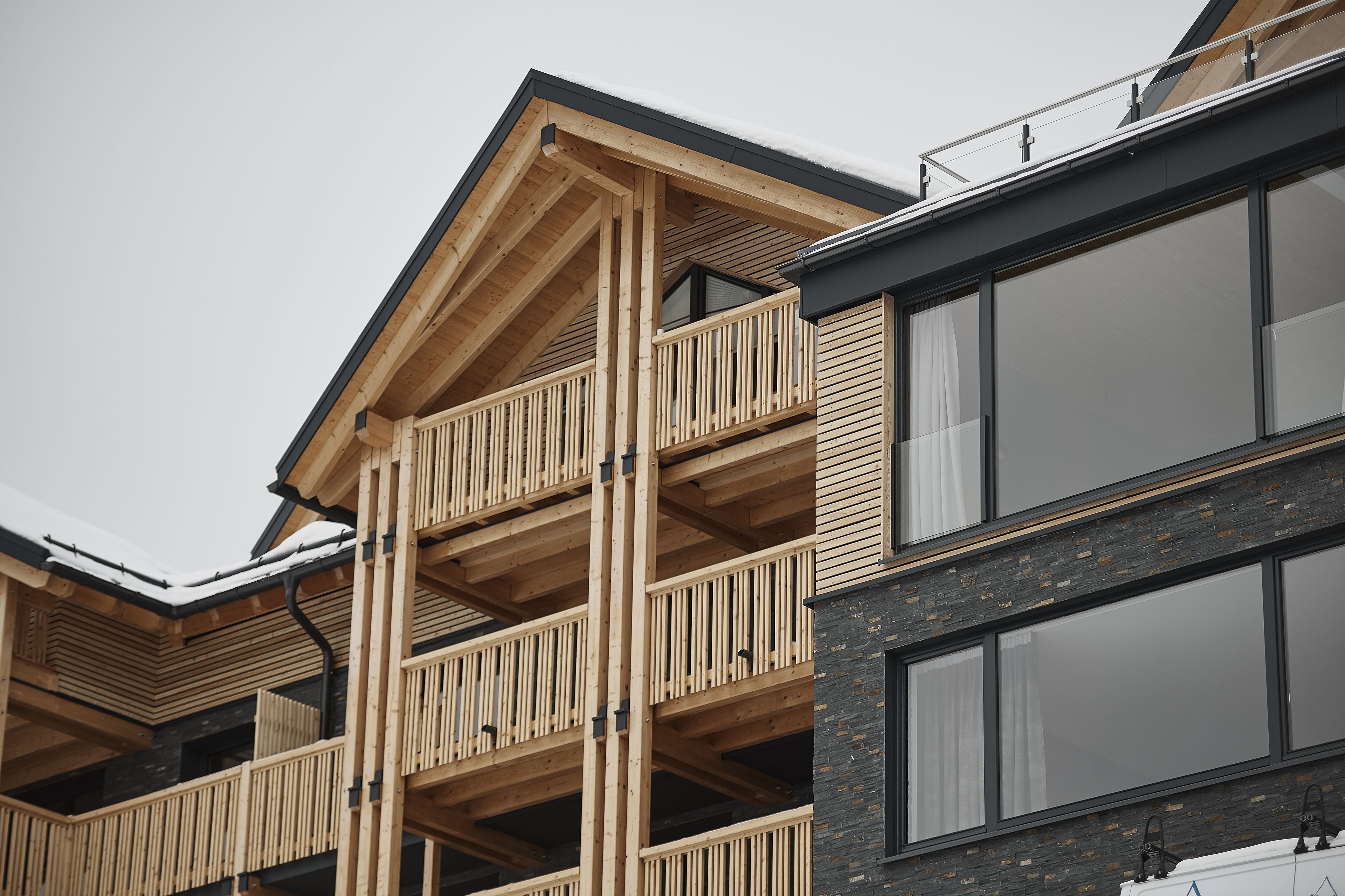 A multi-story building with a wooden balcony structure, large windows, and a modern architectural design.