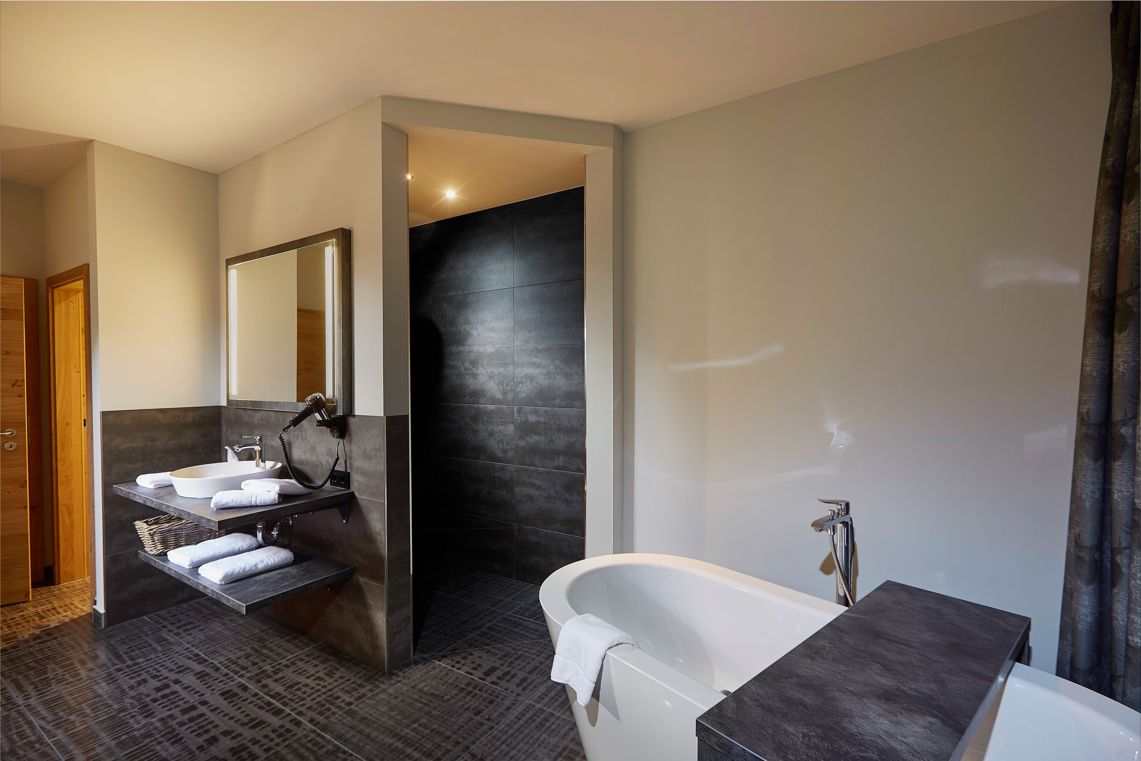 A modern bathroom with a freestanding bathtub, a vanity with a mirror, and a shower area.