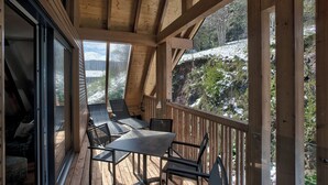 A wooden deck with a table and chairs, overlooking a snowy landscape. - Black Forest Lodge (Feldberg)