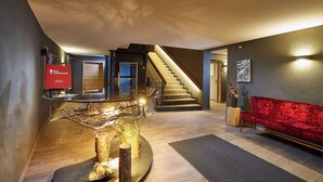A modern interior with a staircase, a red sofa, and a unique tree sculpture centerpiece. - Black Forest Lodge (Feldberg)