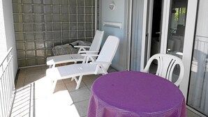A balcony with white lounge chairs, a purple table, and a glass door leading to a patio area. - Ferienwohnung im Atelierhaus (Meersburg)