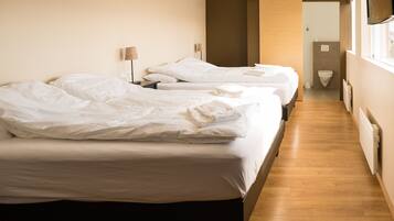 Habitación de hotel con dos camas, piso de madera y vista al pasillo.
