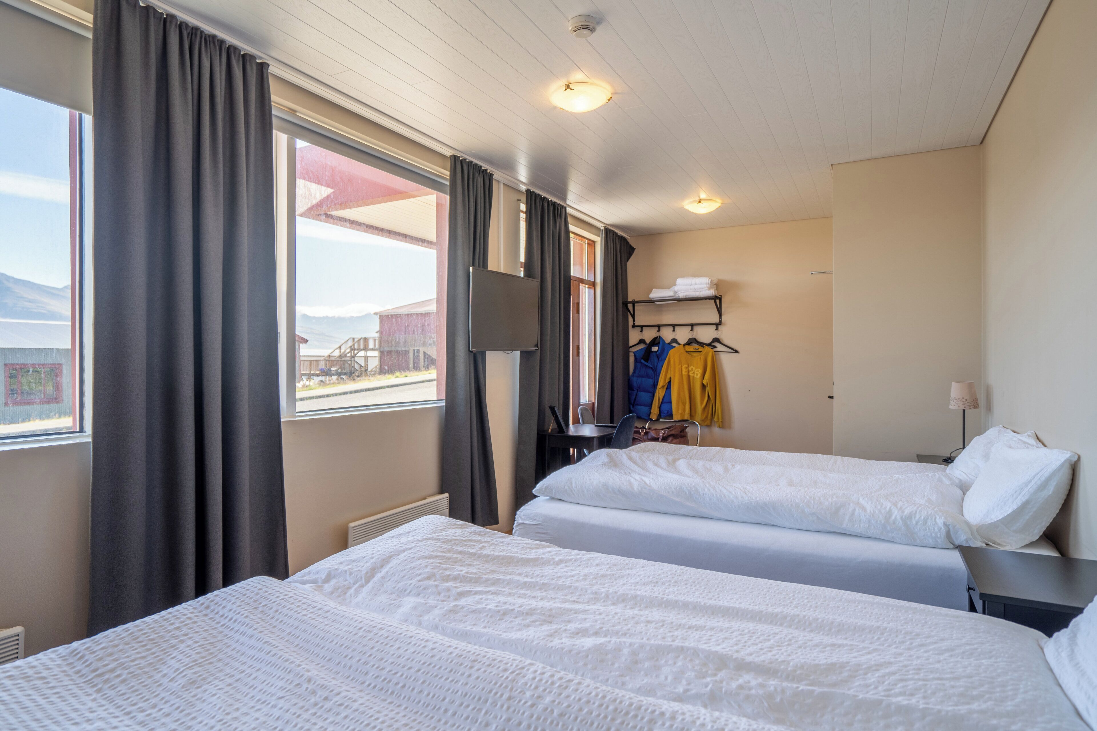 Une chambre d’hôtel avec deux lits, une télévision, un bureau et une vue sur les montagnes.