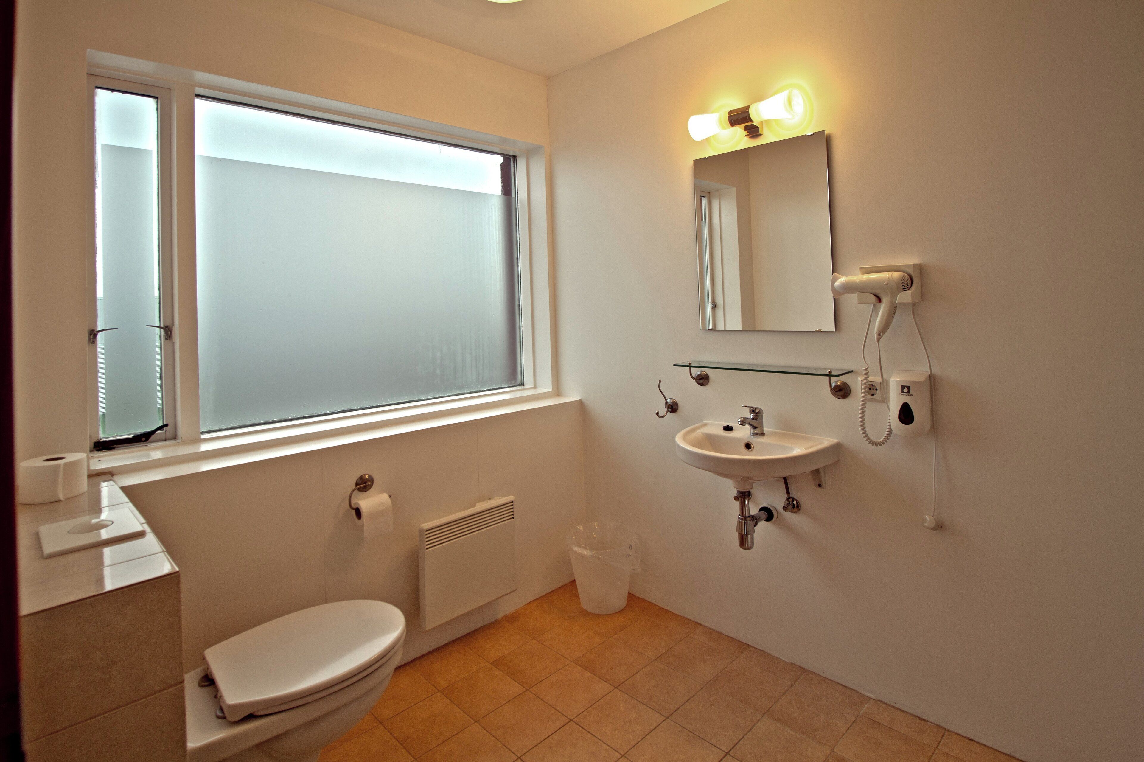 Un baño con inodoro, lavamanos y ventana.