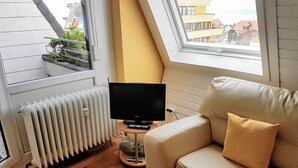 A room with a sofa, a television, and a radiator. - Apartment Seeblick (Meersburg)