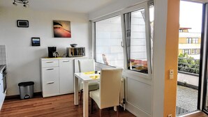 A compact kitchen with a dining area, a microwave, a coffee maker, and a small trash bin. - Apartment Seeblick (Meersburg)