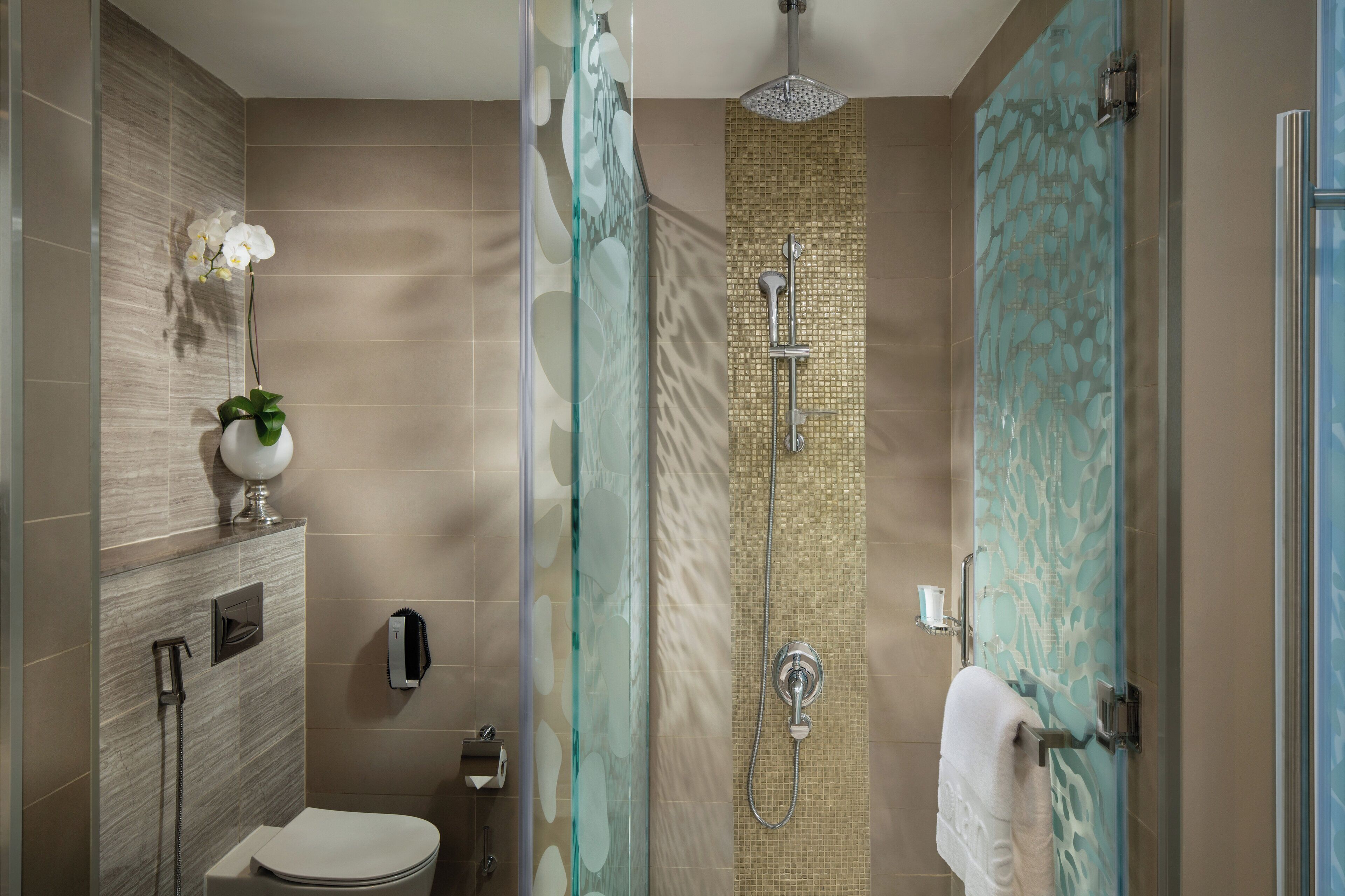 A modern bathroom with a glass-enclosed shower, a toilet, and a sink.
