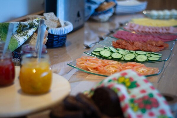 A buffet table with various food items including sliced cucumbers, tomatoes, and different types of meat.