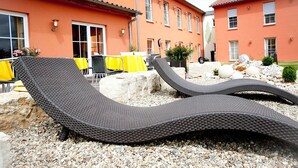 Two reclining lounge chairs in a courtyard with a building in the background.