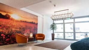 A modern lobby with a large wall mural, a chandelier, and seating areas.