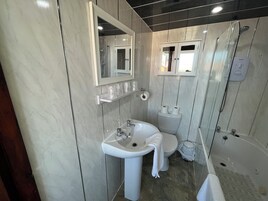 Un baño moderno con tocador de mármol, lavabo, inodoro y zona de ducha.