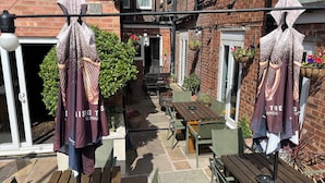 A courtyard with a wooden table and chairs, a hanging coat rack, and a brick building with a window. - Fairhaven Hotel Central Blackpool (Blackpool)