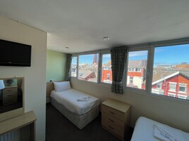 Een hotelkamer met een bed, een dressoir, een televisie en een raam met uitzicht op gebouwen.