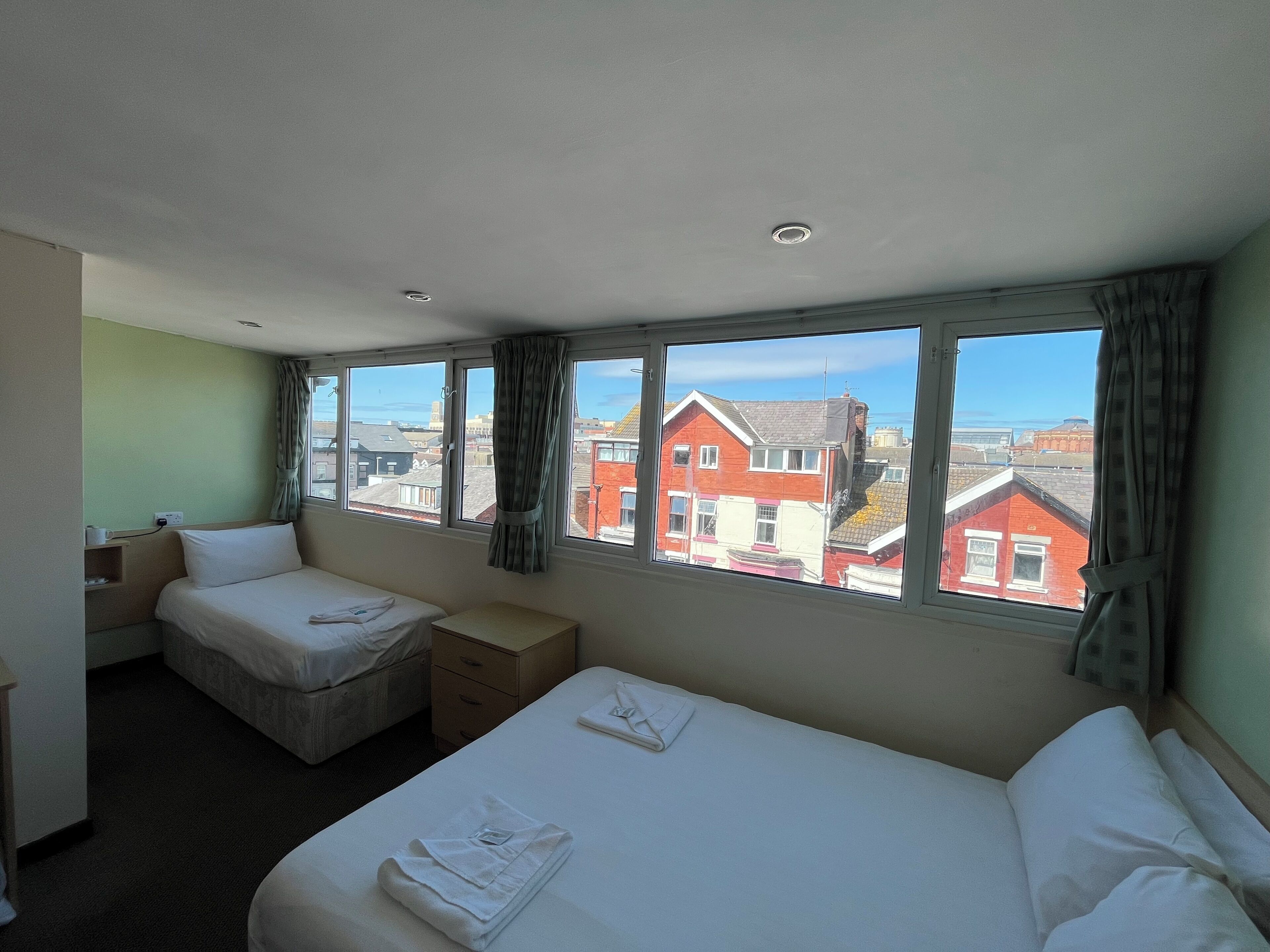 Une chambre d’hôtel avec deux lits, un bureau et une fenêtre donnant sur la ville.