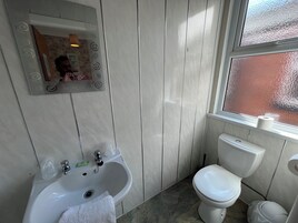 Een badkamer met een wastafel, spiegel, toilet en een raam met uitzicht.