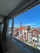 Uitzicht op een rij terrasvormige huizen in rood en roze, met een helderblauwe lucht en de Eiffeltoren op de achtergrond.