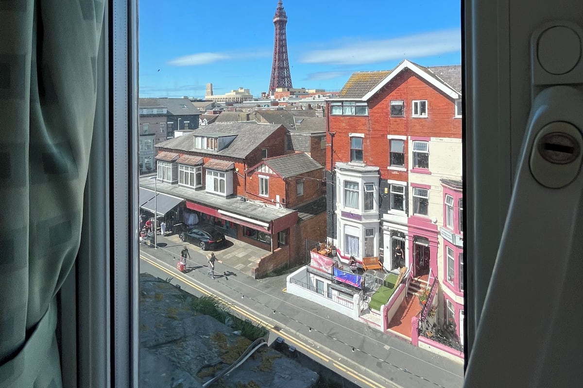 Une vue depuis une fenêtre donnant sur une rue bordée d’immeubles, dont une tour imposante.