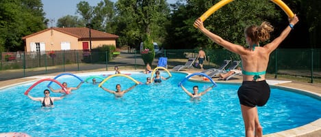 Una piscina al aire libre de temporada, sombrillas, tumbonas