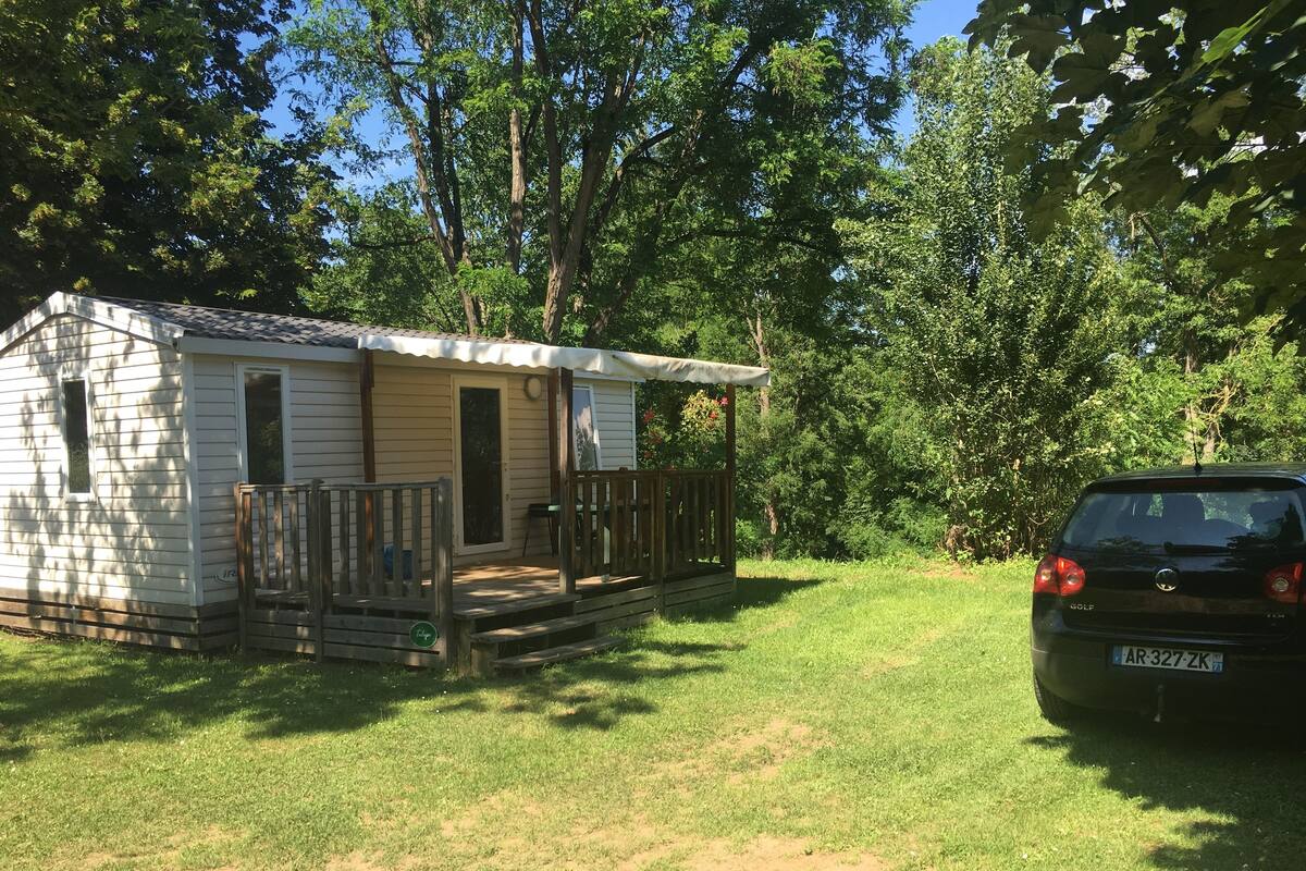 A mobile home with a porch and a car parked nearby.