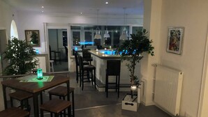 Cocina moderna con barra, taburetes de madera, luces colgantes y una planta en maceta.
