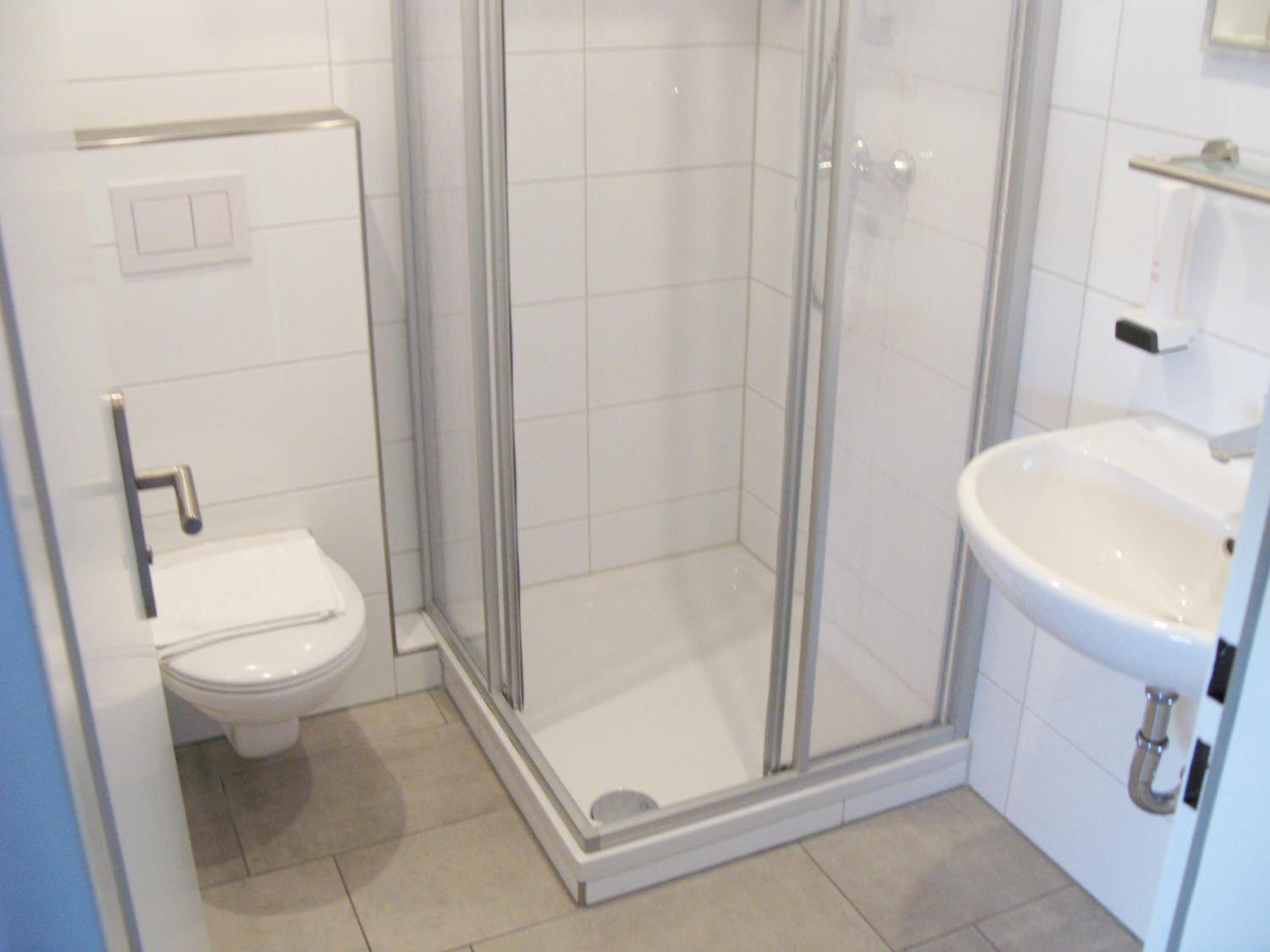 A bathroom with a toilet, a shower enclosure, and a sink.