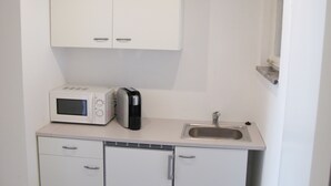 Una pequeña kitchenette equipada con microondas, tostadora y lavabo.