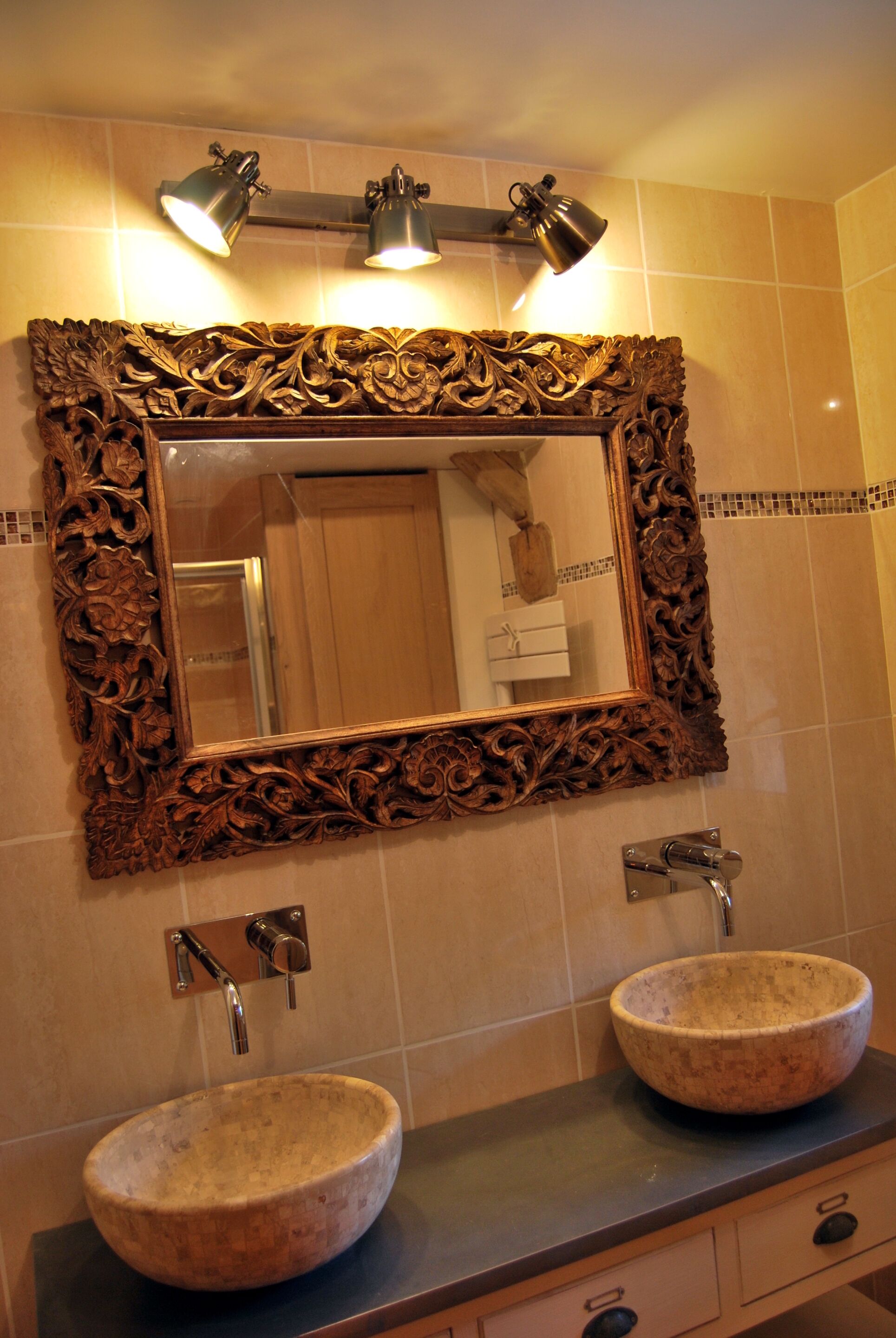 A bathroom with two sinks, a large ornate mirror, and wall-mounted lighting.