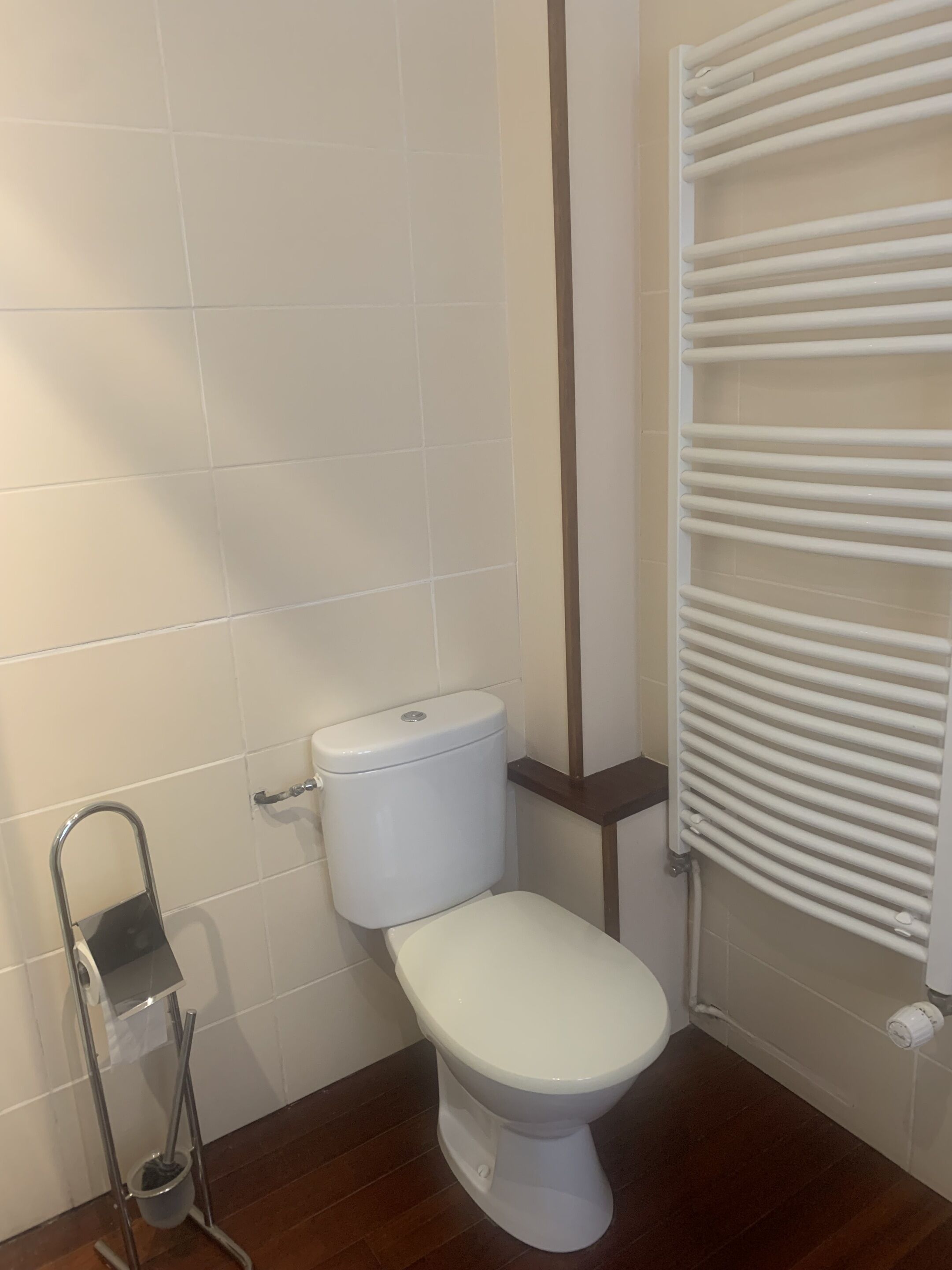 Une salle de bain équipée de toilettes, d’un bidet et d’un porte-serviettes blanc.