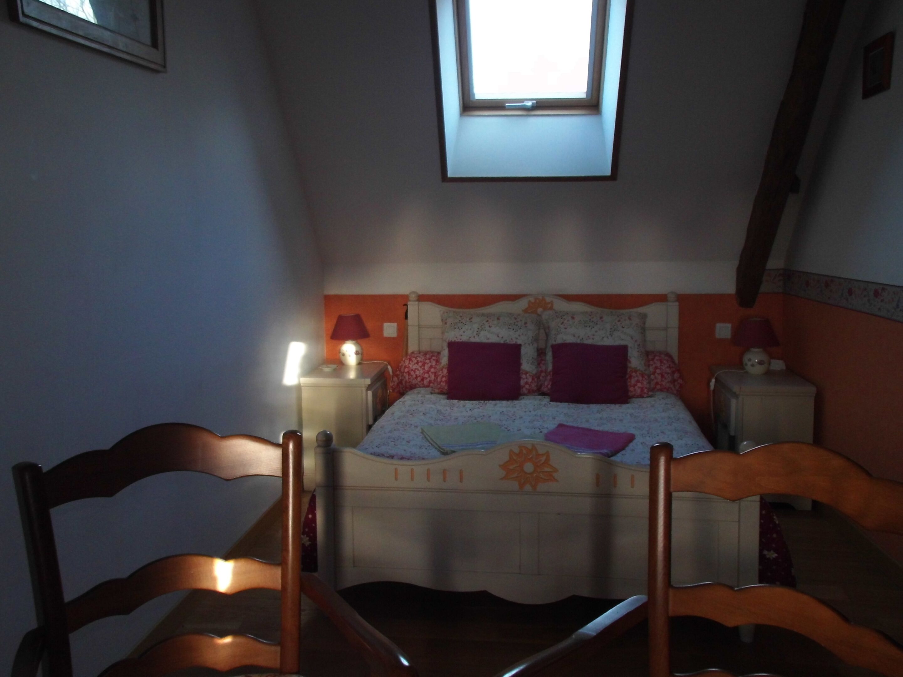 Une chambre avec un lit simple, deux tables de chevet, une commode, une fenêtre et une chaise.