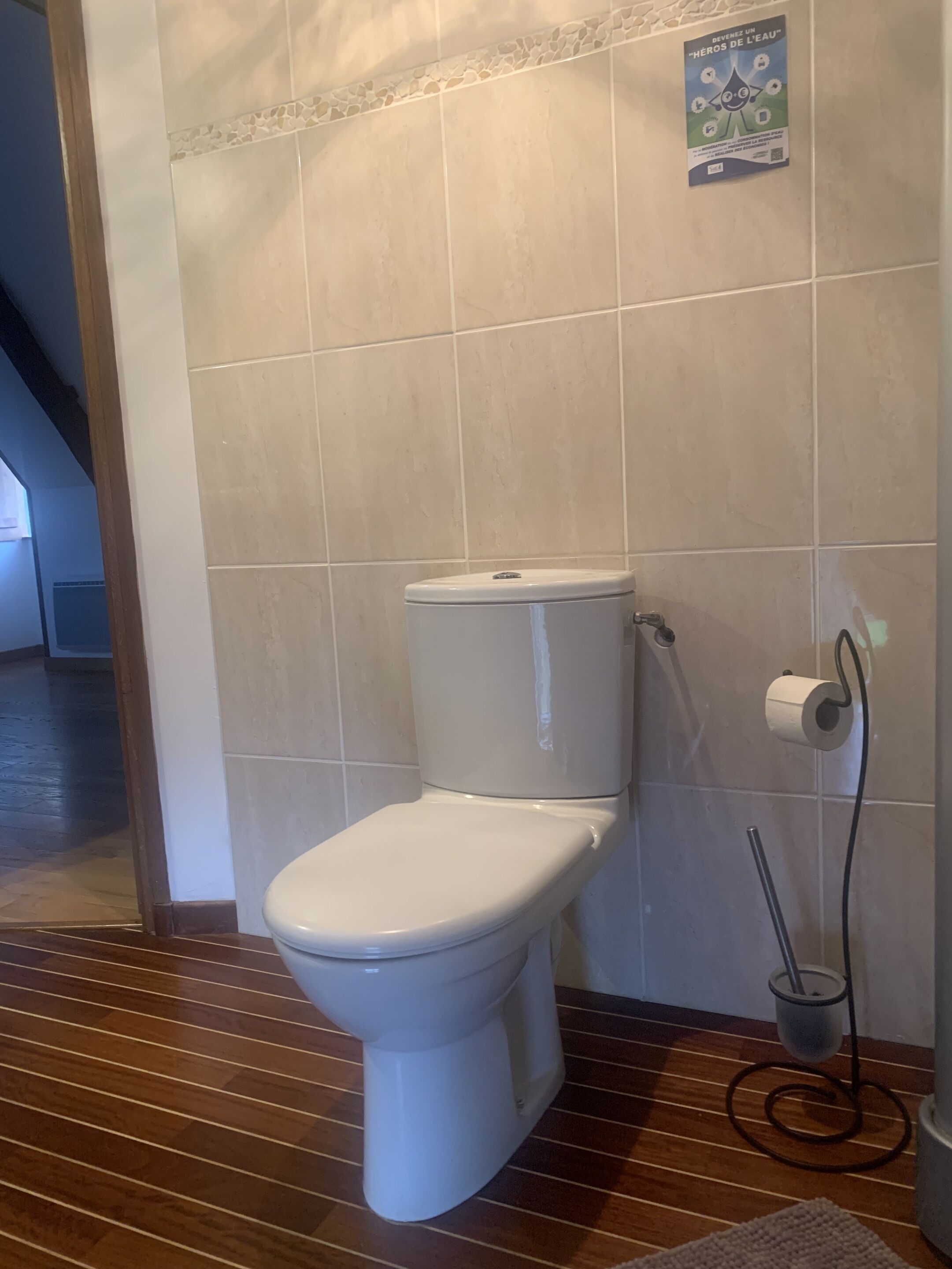 Un bagno con un water bianco, un porta asciugamani di carta e un bidet.