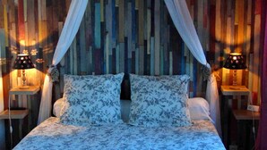 Una cama con ropa de cama floral, un panel de pared de listones de madera y dos lámparas de noche.