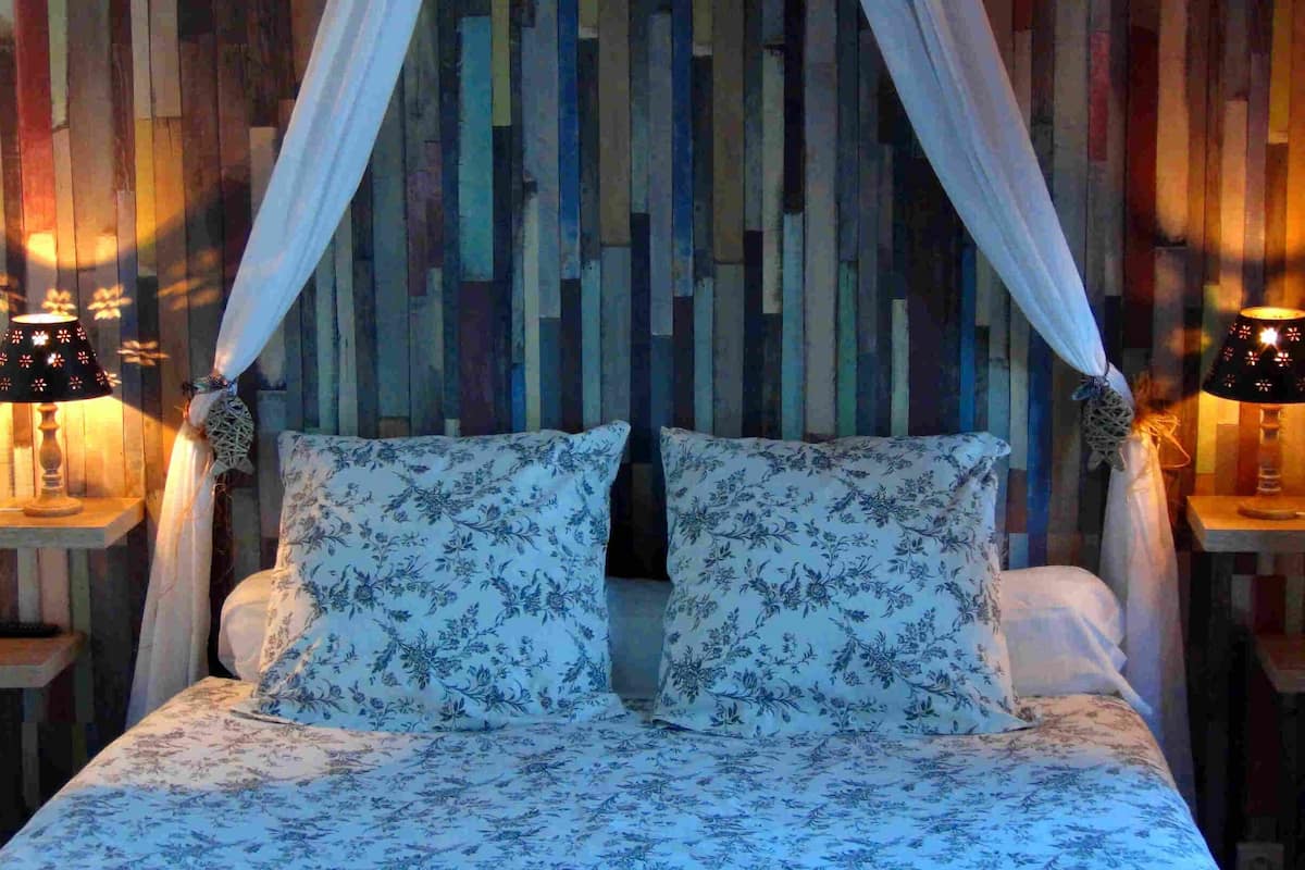 Una cama con ropa de cama floral, un panel de pared de listones de madera y dos lámparas de noche.