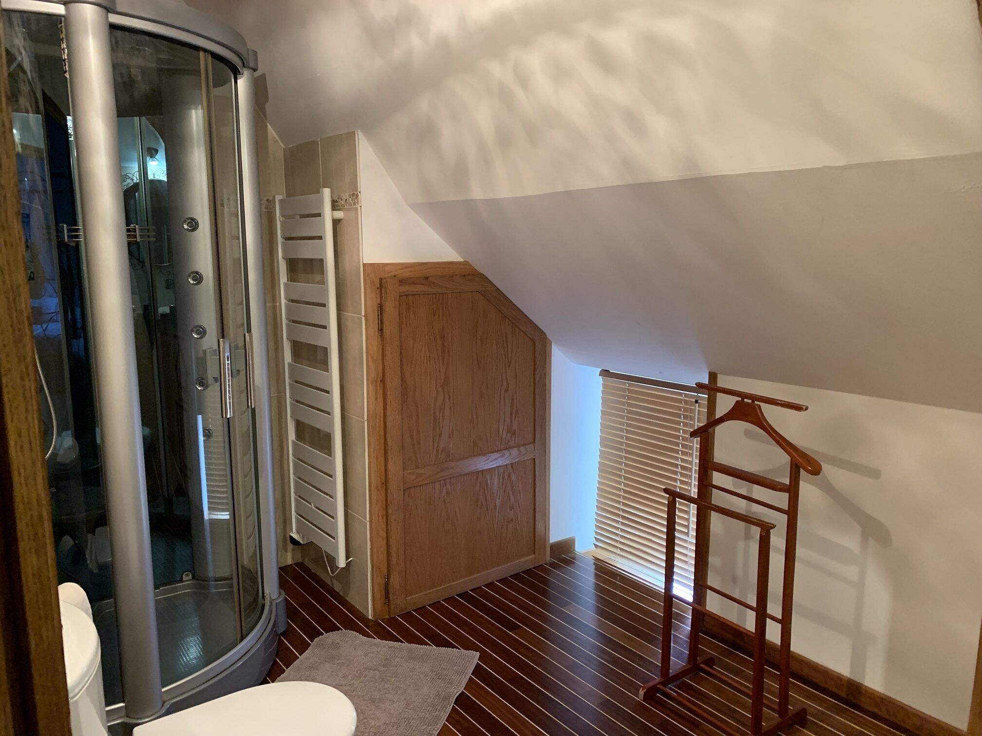 Un bagno con box doccia in vetro, un armadietto in legno e una scala di legno.