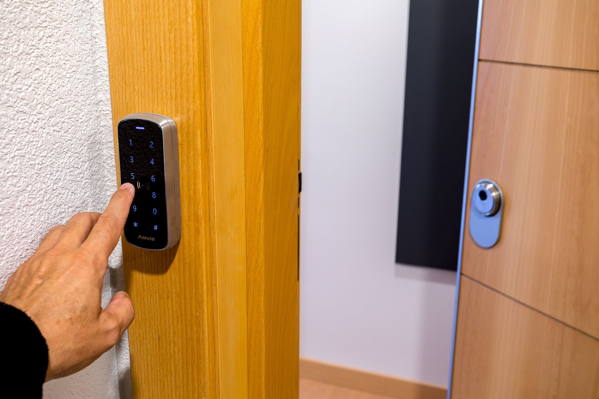 A hand using a numeric keypad on a door lock.