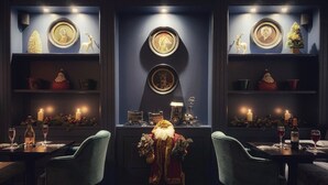 Un comedor cálidamente iluminado con dos mesas, sillas y una pieza decorativa central.
