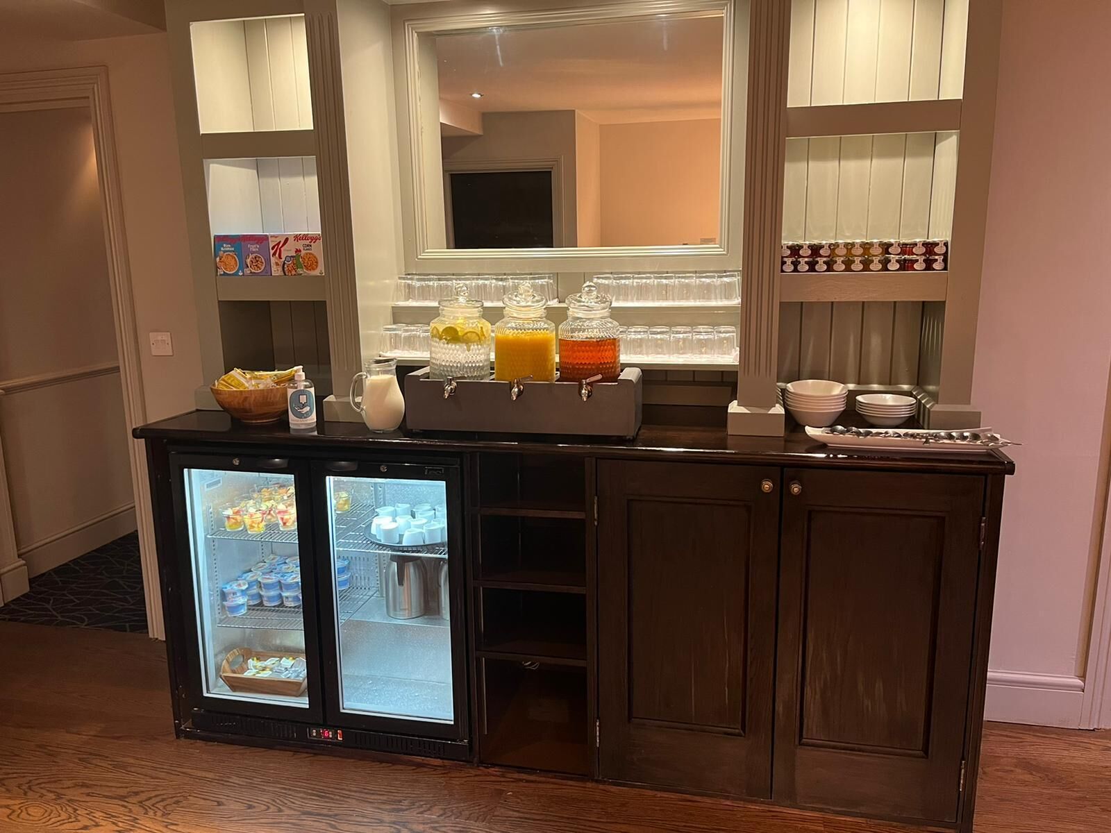 A hotel room with a breakfast bar featuring a mini-fridge, a coffee maker, and a juice dispenser.