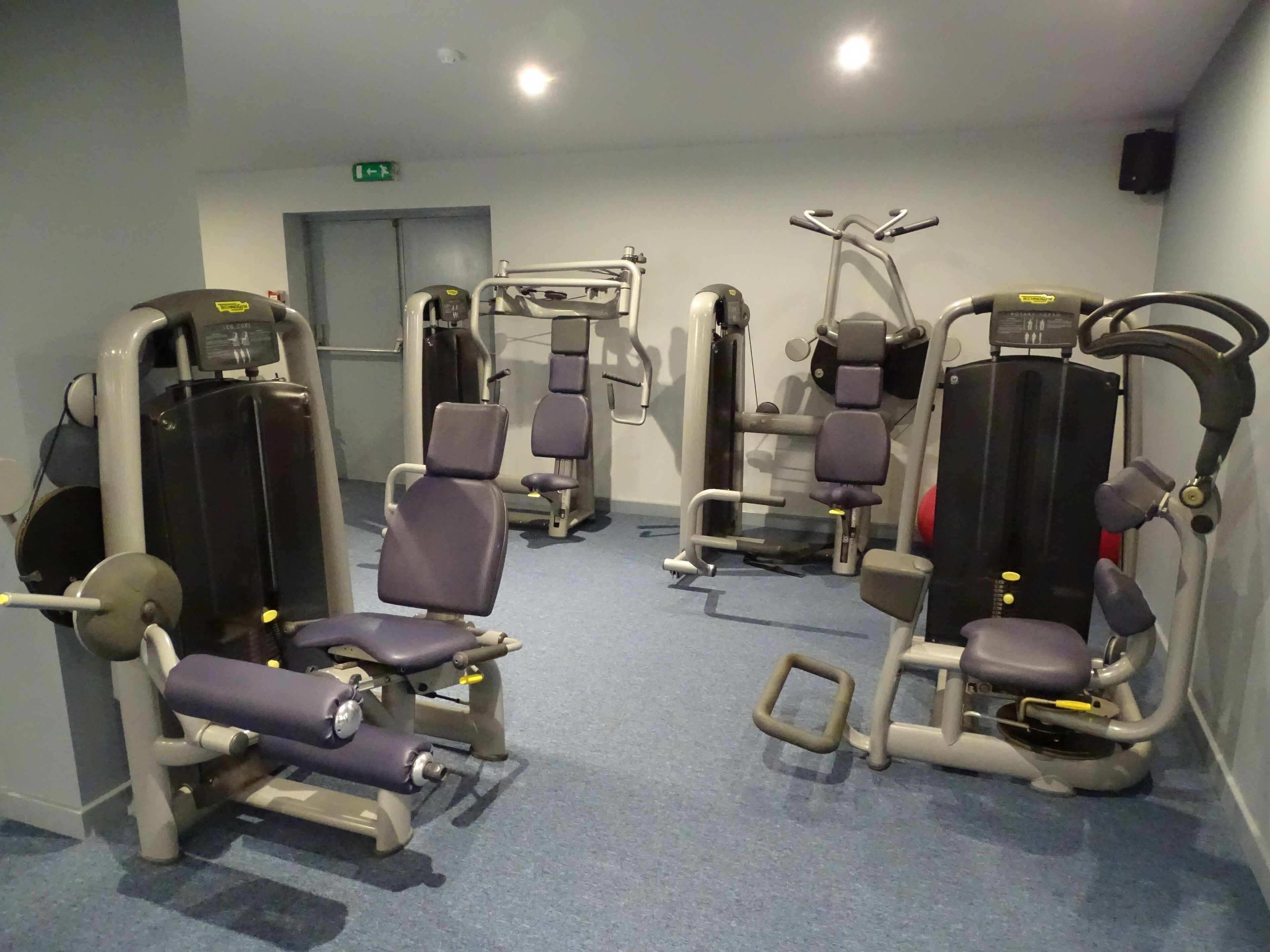 Ett gym med olika träningsmaskiner, inklusive styrketräningsmaskiner och konditionsutrustning.