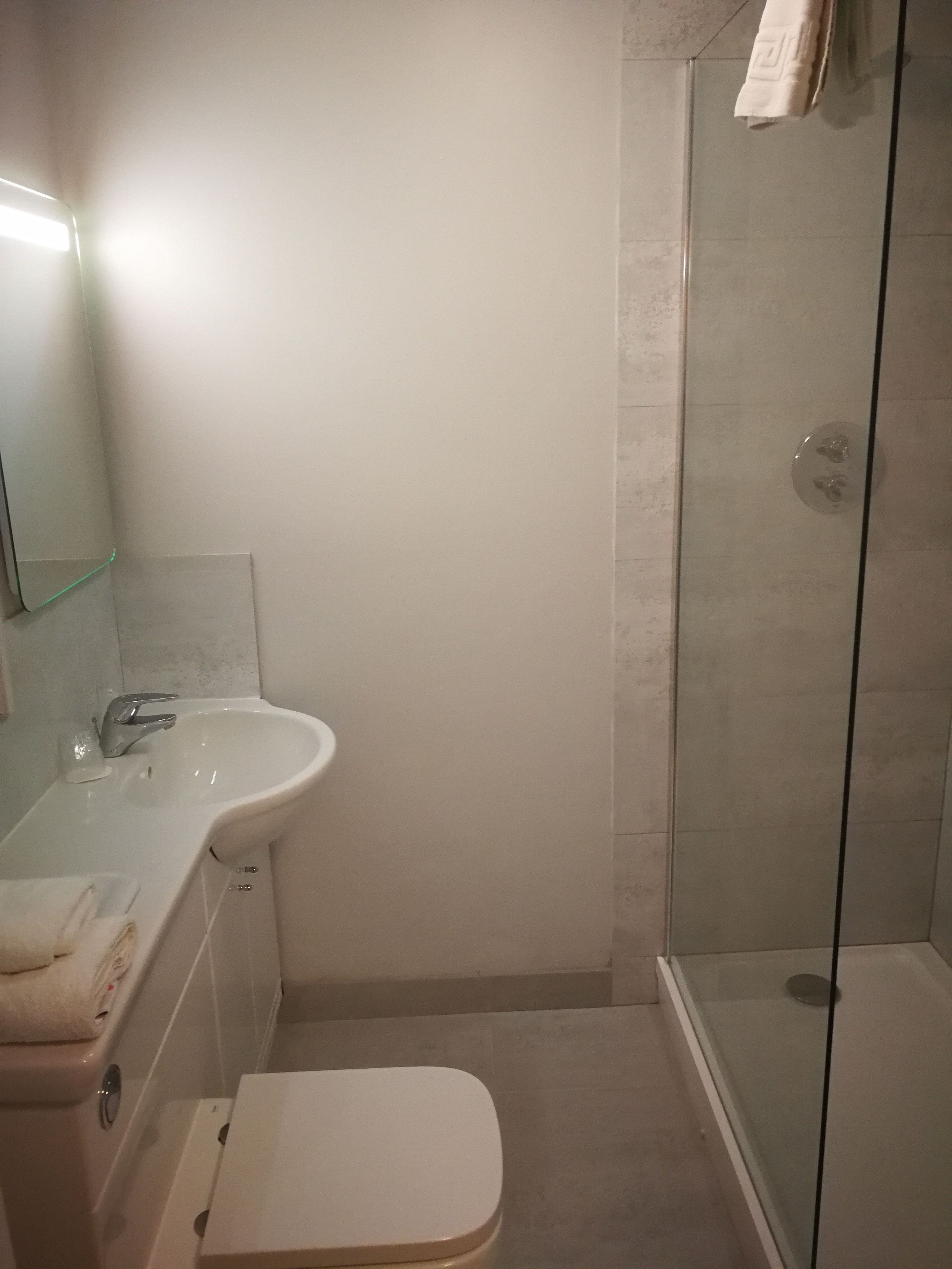 A bathroom with a sink, toilet, and glass shower enclosure.