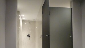 Un baño moderno con mampara de vidrio, una puerta oscura y suelo de baldosas.