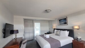 Una habitación de hotel con cama, mesita de noche, lámpara y un cuadro en la pared.