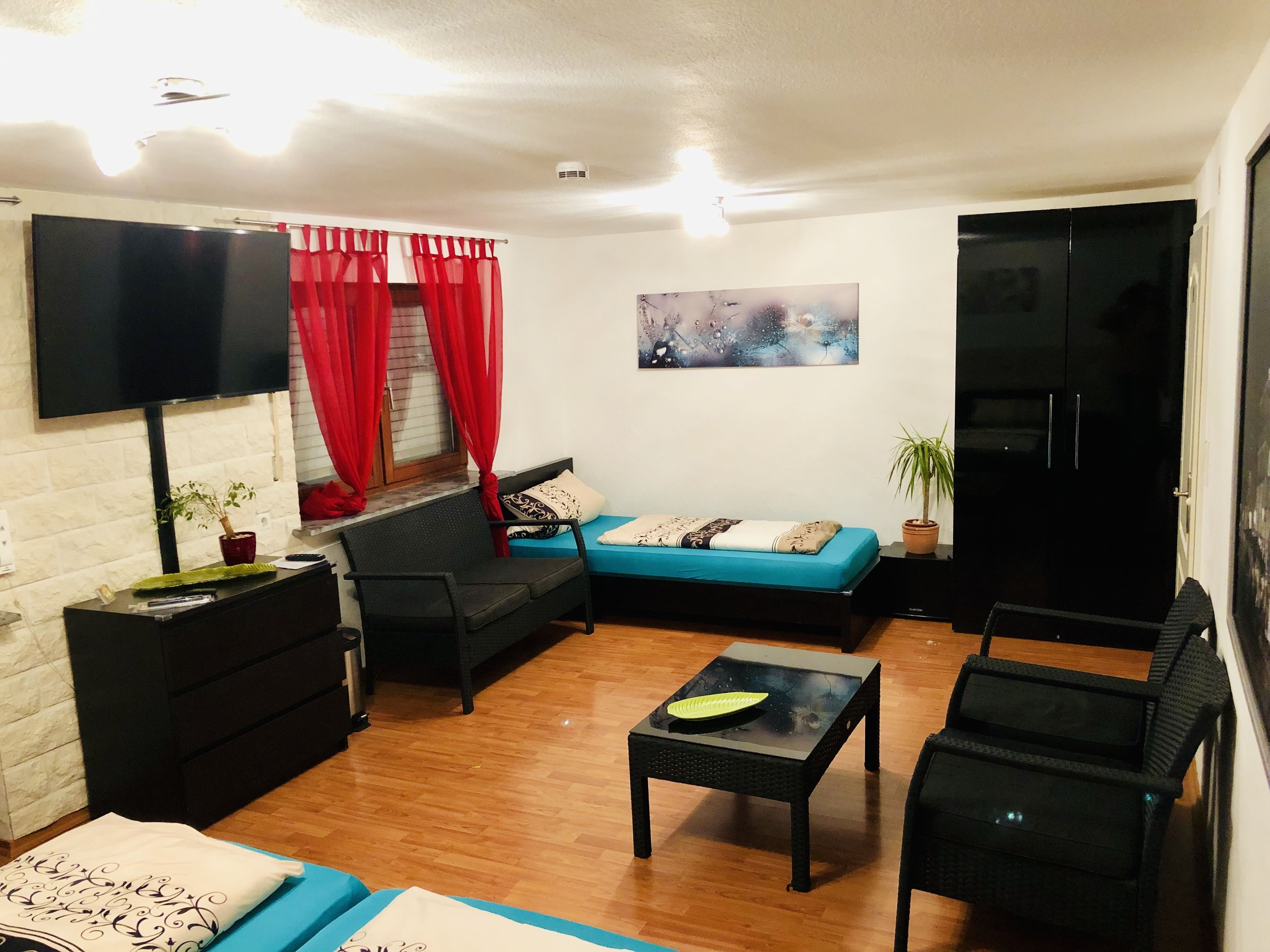 A living room with a sofa, chairs, a TV, a painting, and a cabinet.
