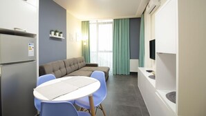 A modern, compact living space with a kitchenette, a sofa, a dining table, and a TV. - KNJZ Seaview Apartment (Batumi)
