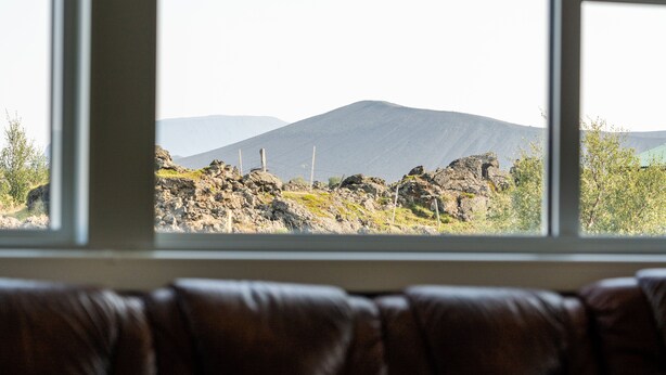 A view through a window of a rocky landscape with mountains in the distance. - Vogar Travel Service (Myvatn)