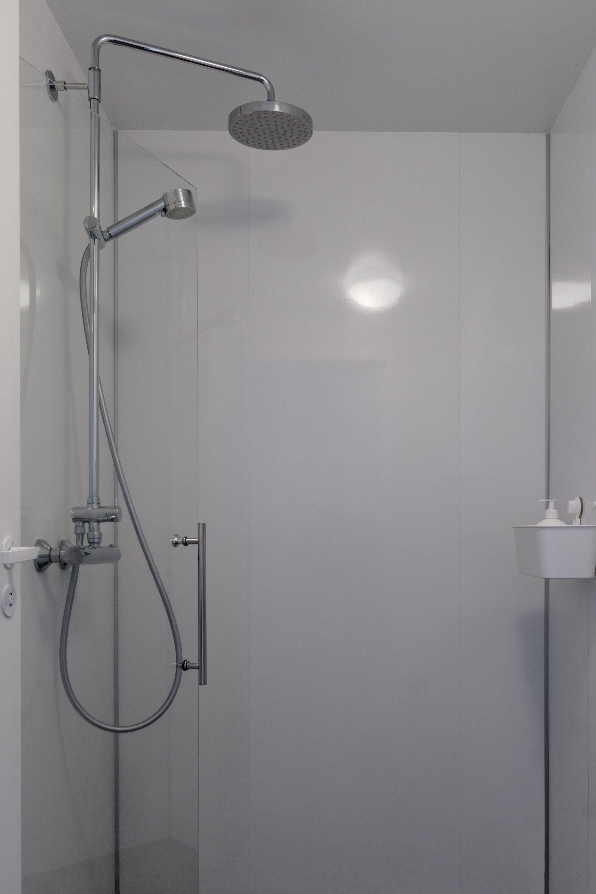 A modern shower with a handheld showerhead and a wall-mounted rain showerhead.