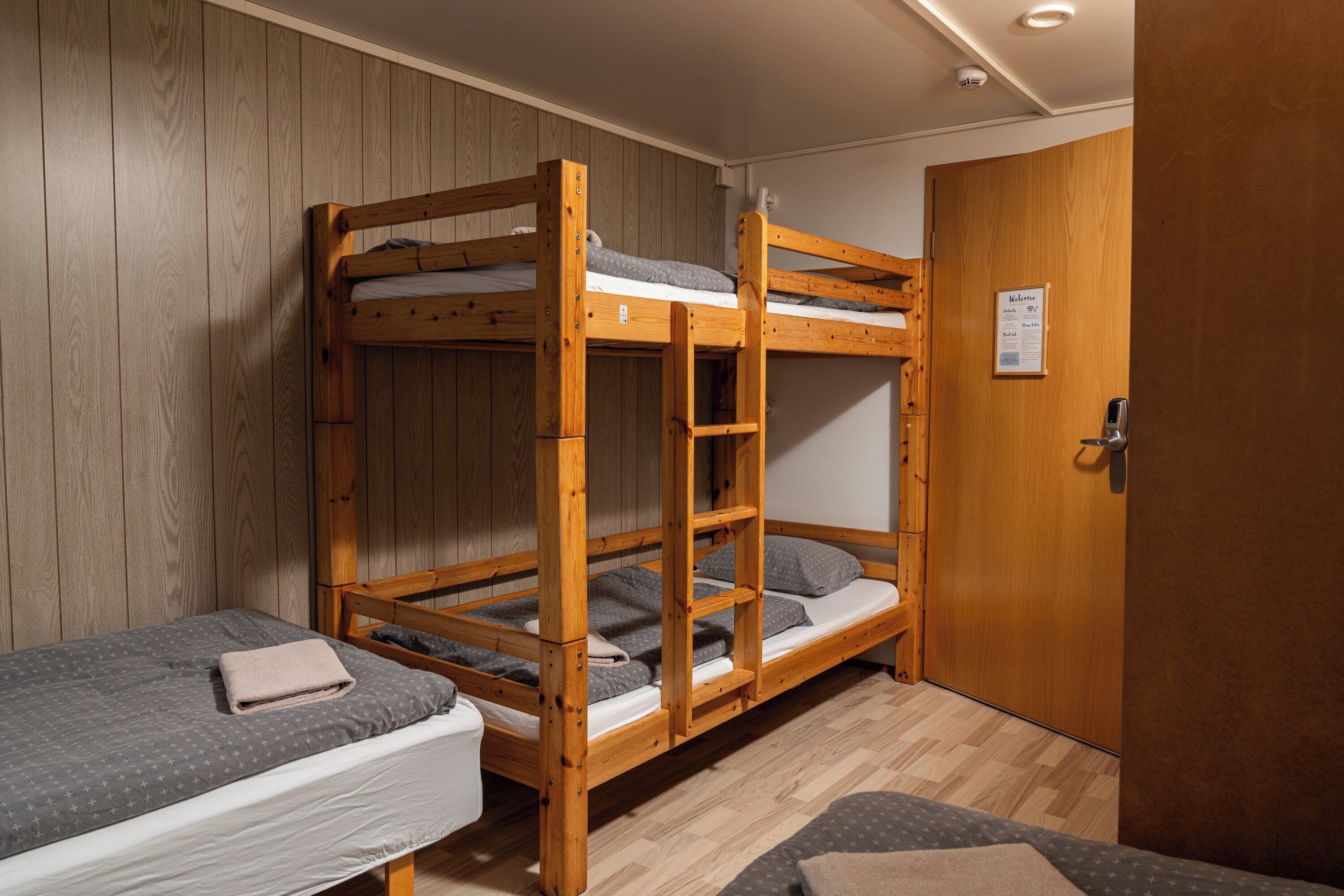 Una habitación con dos literas, una puerta de madera y un letrero en la pared.