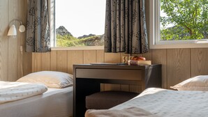 A bedroom with two beds, a desk with a chair, and a window with curtains. - Vogar Travel Service (Myvatn)