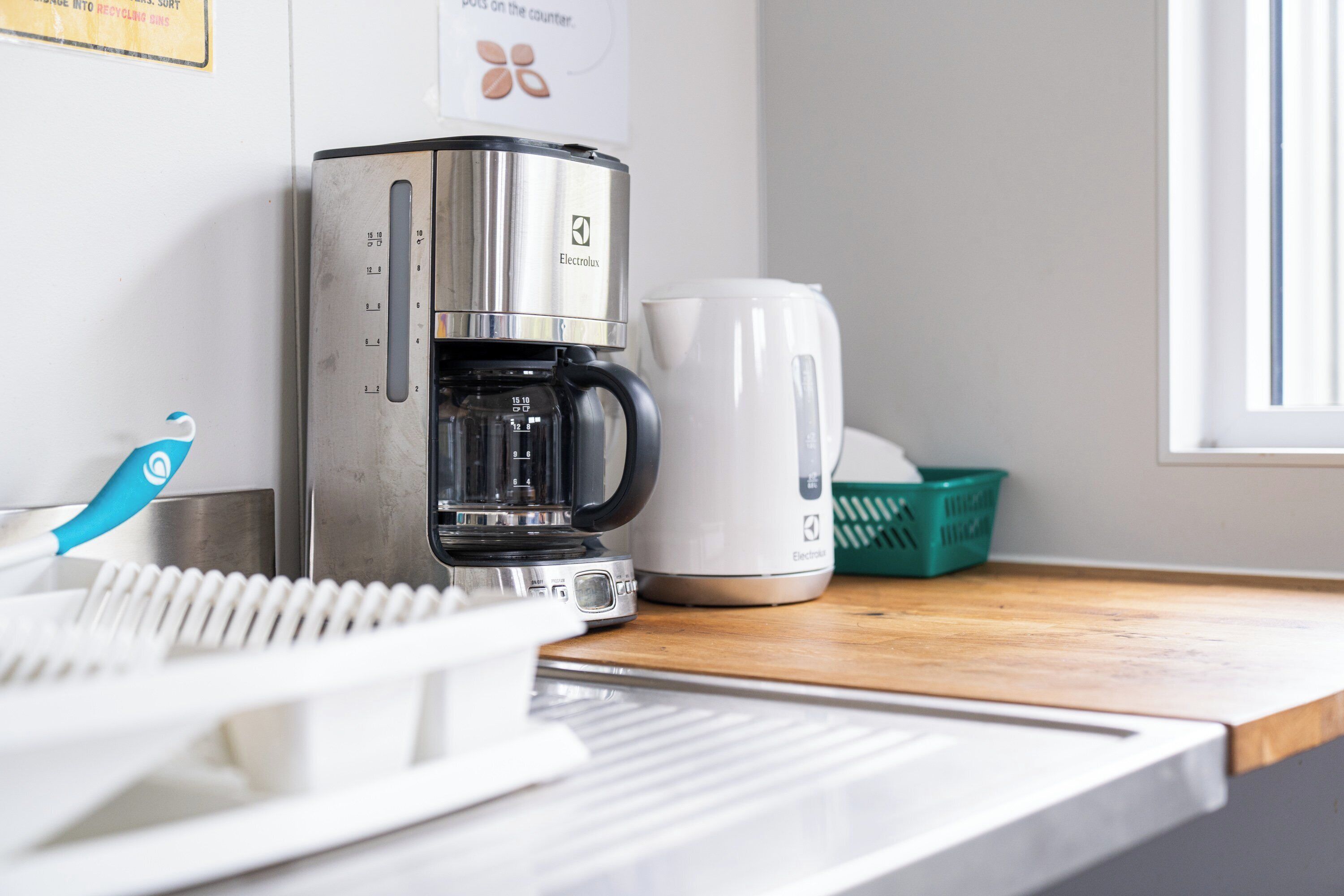 A coffee maker, a kettle, and a basket on a kitchen counter.